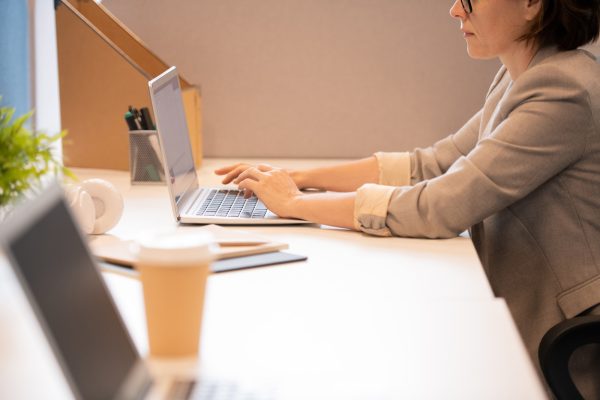 Close-up of serious busy lady in jacket sitting at desk